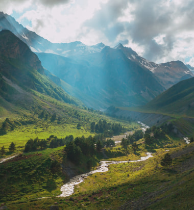 Река, протекающая через долину с горами на заднем плане.